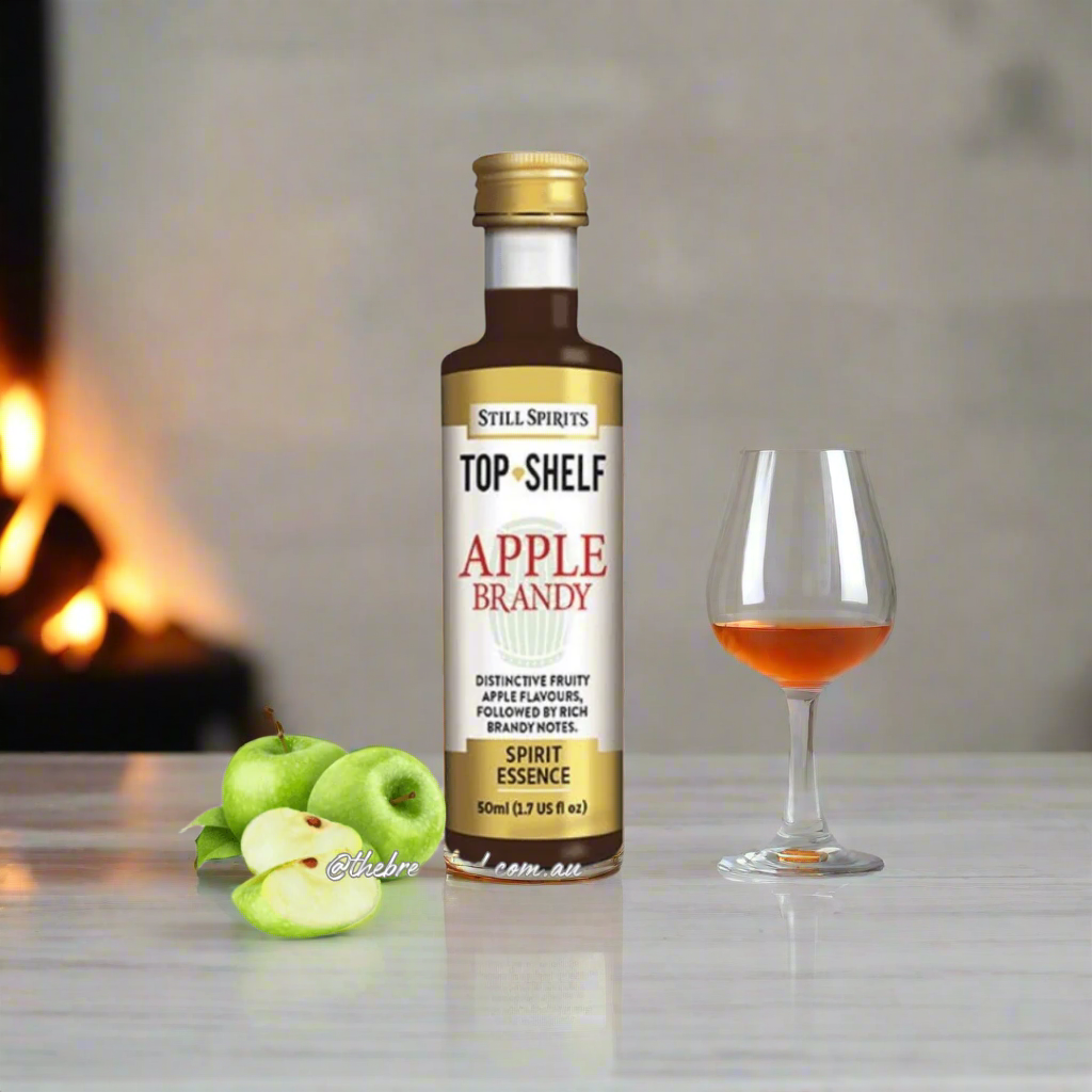 bottle filled with dark liquid and apples resting next to it