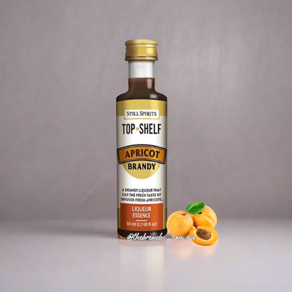 clear bottle with gold cap, brown liquid inside, apricot next to bottle