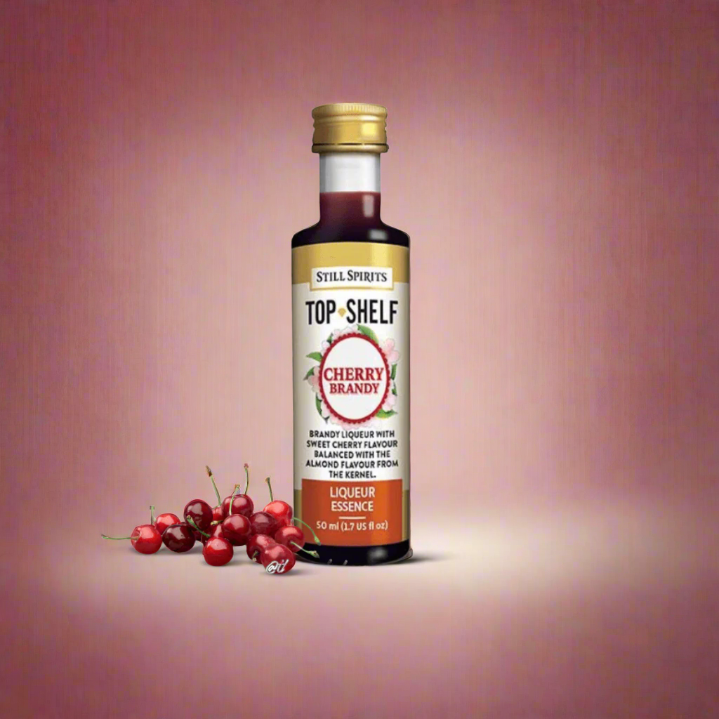 clear bottle with deep red liquid inside and cherries resting next to bottles