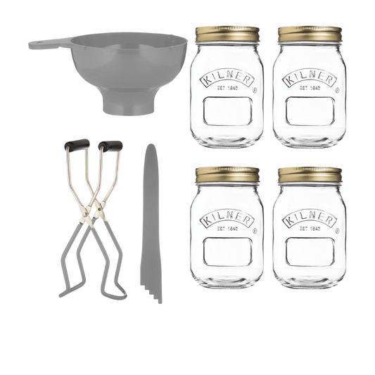 four glass jars with lids and other equipment for preserving food